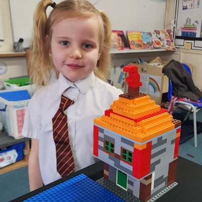 KS1 Student showing off LEGO Tudor House